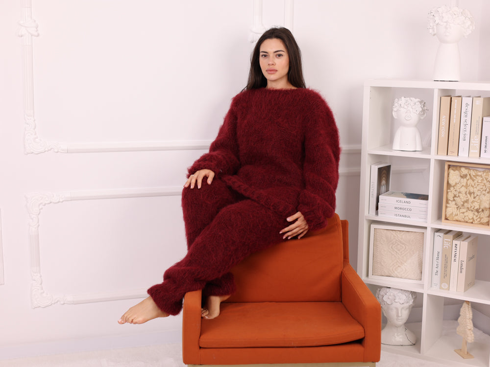 Woman wearing a red lounge set sitting on an orange chair in a room with a bookshelf.