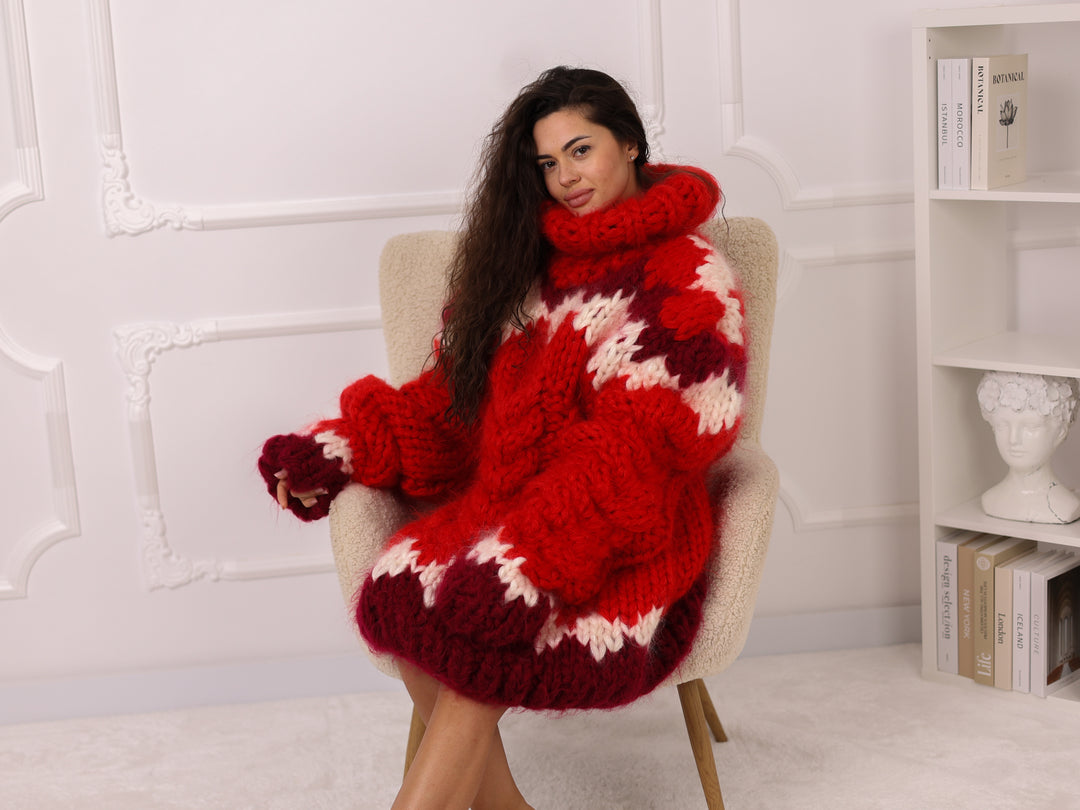 Woman wearing a red and white patterned sweater sitting on a chair in a room with a white wall and bookshelf.