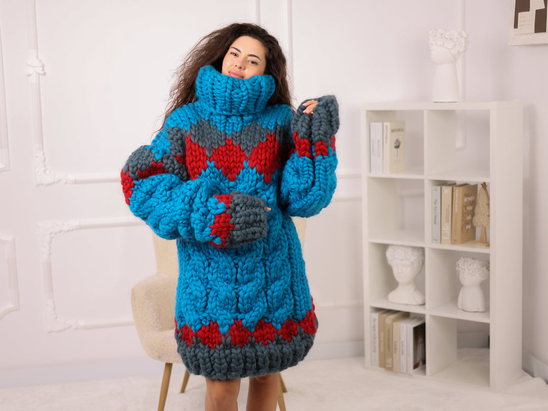 Person wearing a blue and gray patterned sweater with red accents in a room.