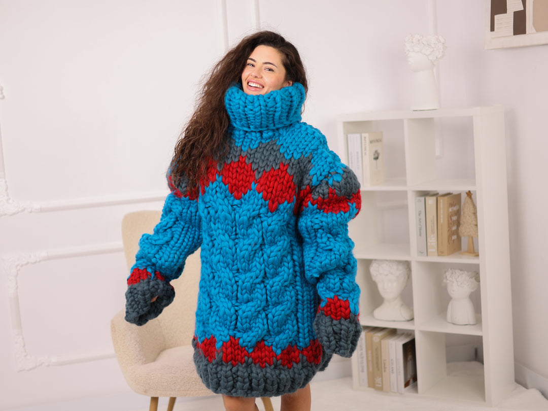 Woman wearing a blue and red knitted sweater in a room with a white wall and bookshelf.