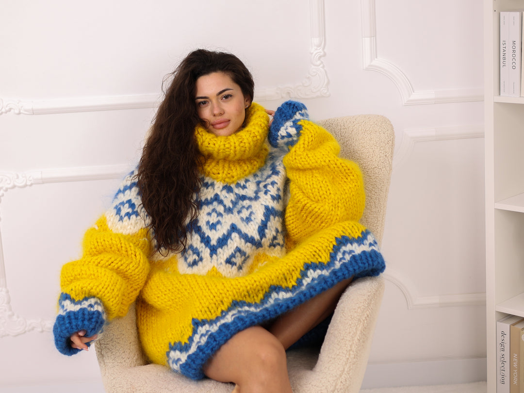 Woman wearing a yellow and blue patterned sweater sitting on a white chair.