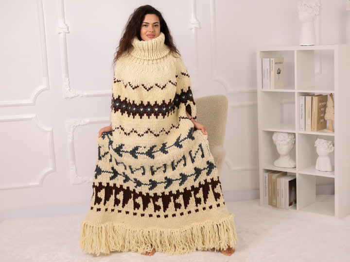 Woman wearing a long, patterned sweater dress in a room with a white bookshelf.