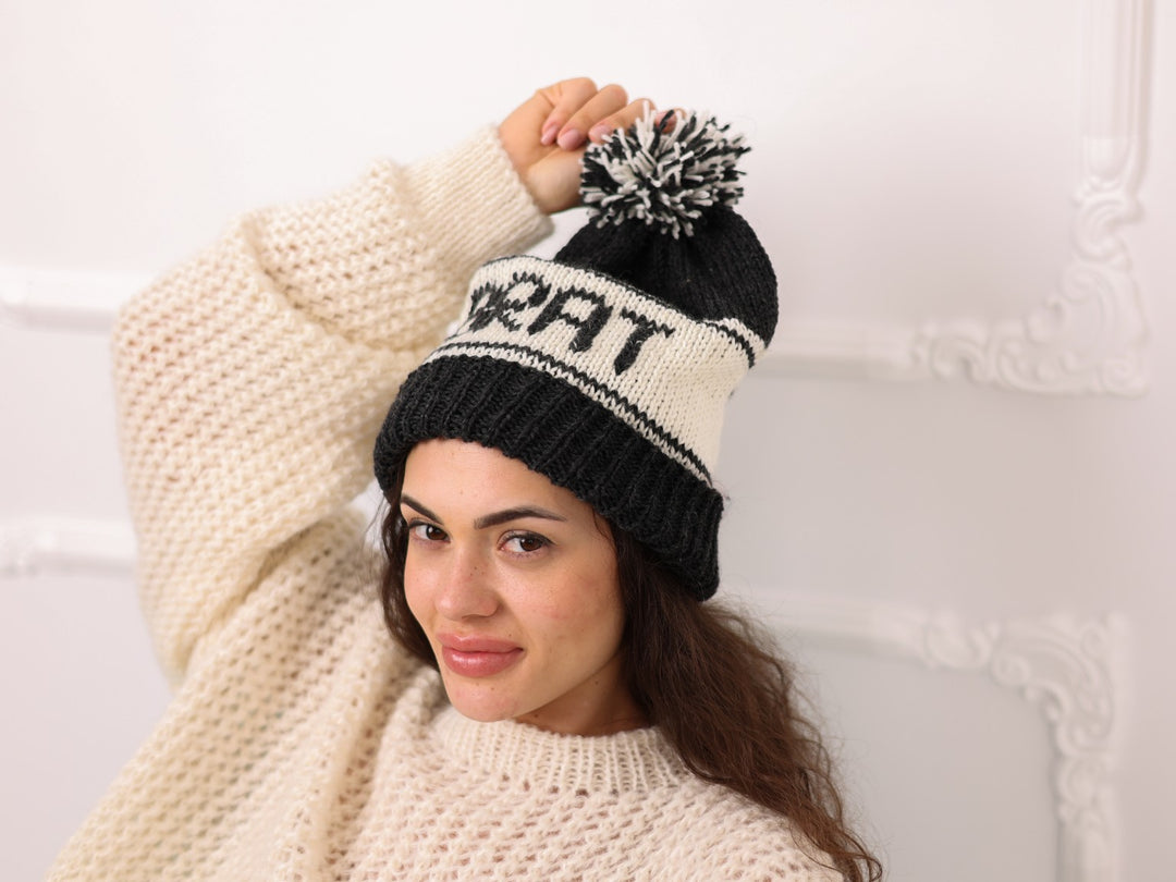 Angled view of black cream soft wool personalized BRAT knit beanie