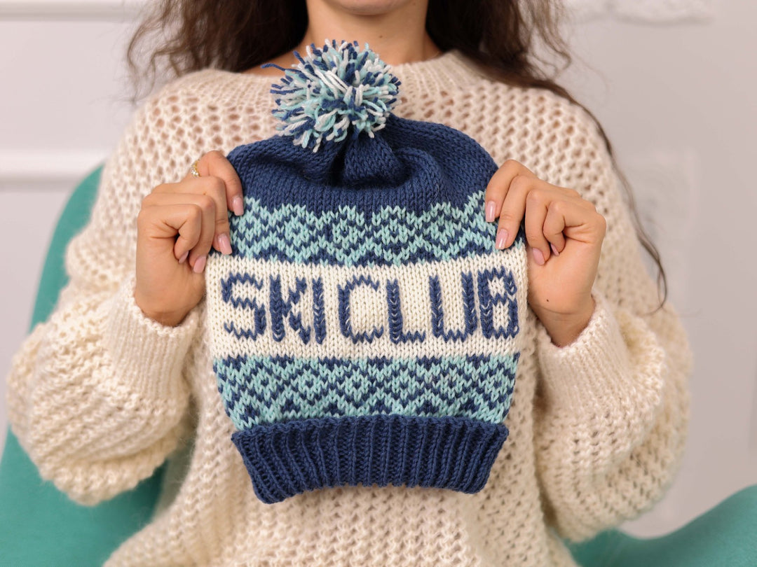 Hand held blue and cream soft wool beanie with SKI CLUB text and pom pom