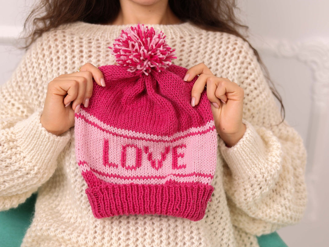 Hand held pink soft wool beanie with LOVE text and pom pom