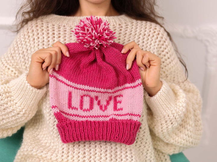 Hand held pink soft wool beanie with LOVE text and pom pom