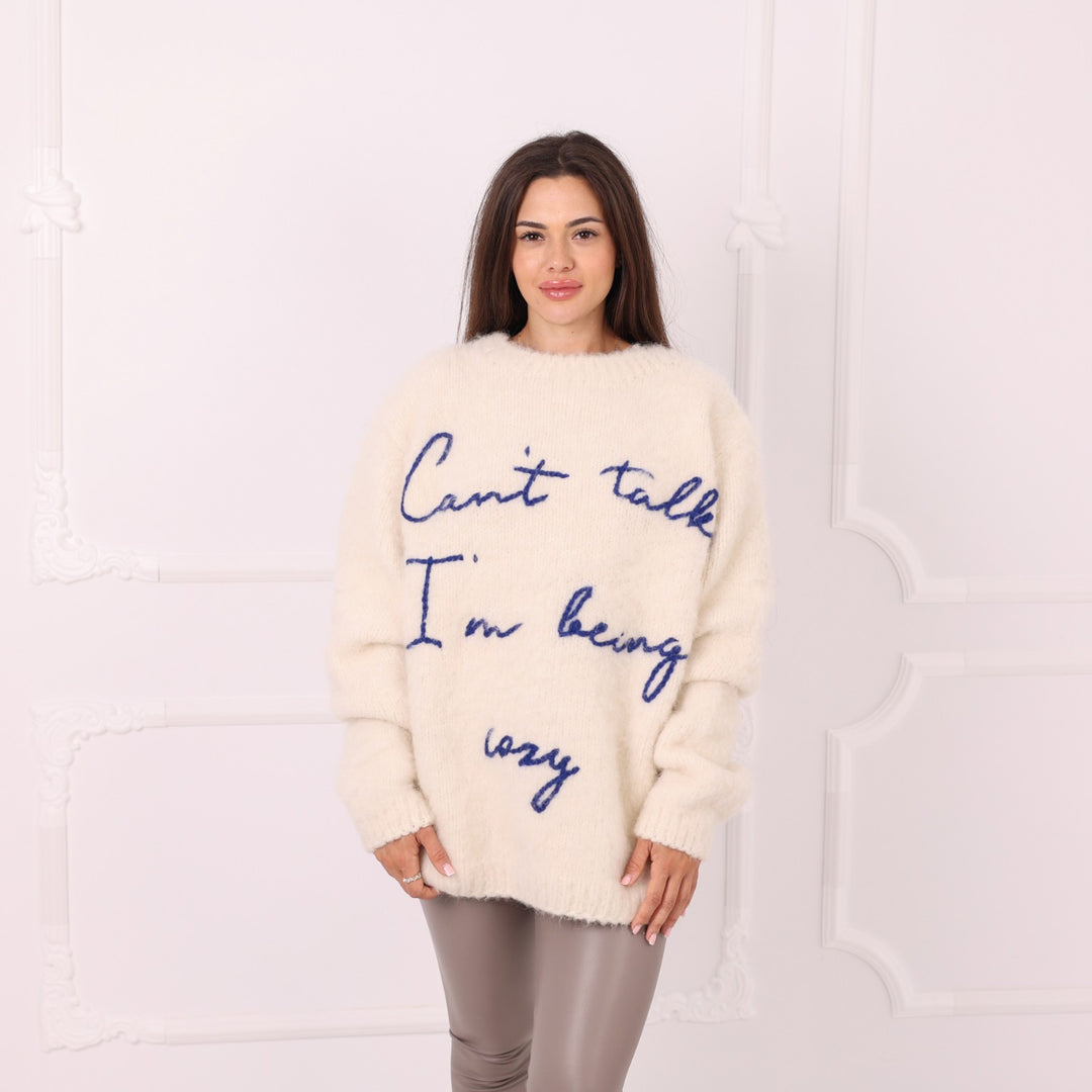 Model wearing personalized cream alpaca sweater with blue text