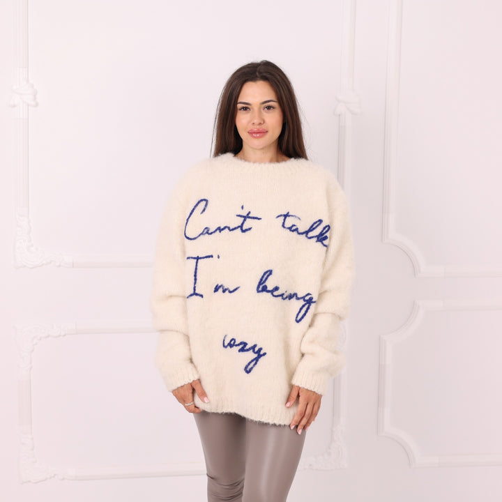 Model wearing personalized cream alpaca sweater with blue text