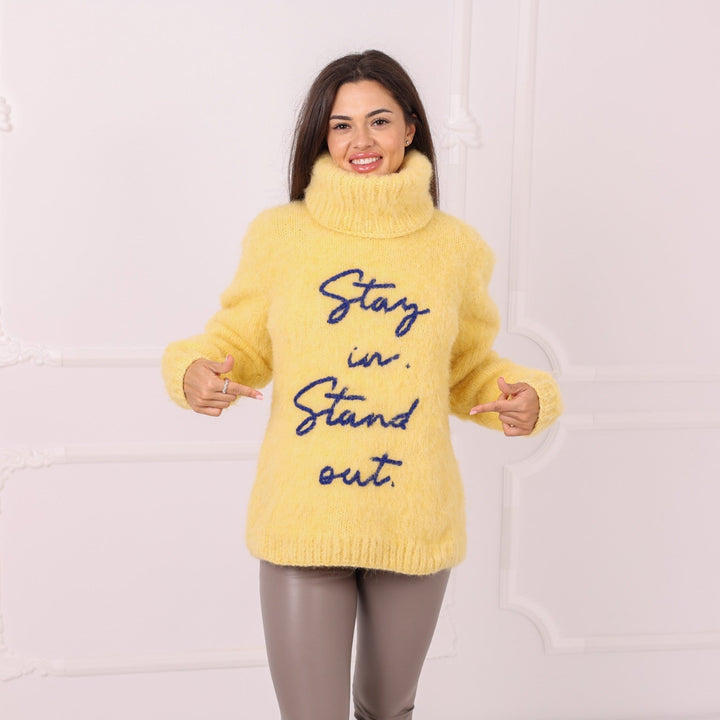 Model wearing personalized yellow alpaca sweater with blue lettering
