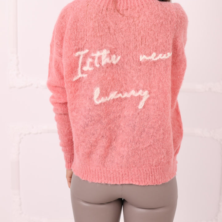 Back close up of pink baby alpaca sweater with white custom text